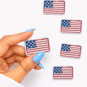 May include: Embroidered patches featuring the American flag. Each patch has a blue field with white stars and red and white stripes. The patches are rectangular with a white border.