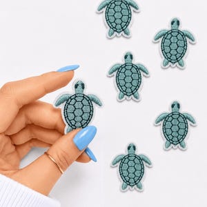 May include: A collection of six small, embroidered sea turtle patches. Each patch features a light teal body with dark teal thread detailing the shell pattern and a white border. The turtles are depicted in a top-down view with flippers extended.