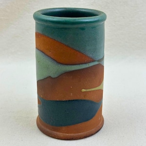 May include: A cylindrical ceramic vessel featuring a matte finish with abstract, flowing bands of terracotta, sage green, and dark teal glaze. The rim is rounded and finished in a solid dark teal, while the base is slightly flared and unglazed.
