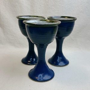 Puede incluir: Un juego de tres tazas de cerámica con un acabado moteado y mate. Las tazas son de color crema, gris claro y gris oscuro. Cada taza tiene un diseño simple y minimalista, ideal para café o té.