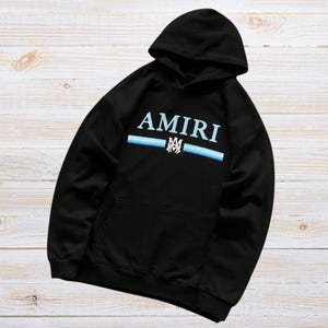 Unisex AMIRI-style hoodies in black and white with bold front graphic and stripe design, pullover streetwear sweatshirts with hood and kangaroo pocket.