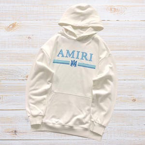 Unisex AMIRI-style hoodies in black and white with bold front graphic and stripe design, pullover streetwear sweatshirts with hood and kangaroo pocket.