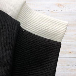 Unisex AMIRI-style hoodies in black and white with bold front graphic and stripe design, pullover streetwear sweatshirts with hood and kangaroo pocket.