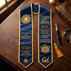 May include: A navy blue graduation sash with gold trim and lettering. The sash features the University of California, Berkeley seal, the text "Class of 2028", and the Cal logo. It also includes the text "Bachelor of Arts".