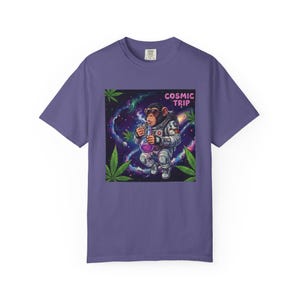 Puede incluir: Camiseta morada con un gráfico de un chimpancé con un traje espacial sosteniendo un vaso de precipitados, sobre un fondo cósmico. El texto "COSMIC TRIP" está encima de la imagen. Hojas verdes de cannabis a los lados.