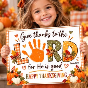 May include: A rectangular sign with a white background and orange plaid border featuring the text Give thanks to the LORD for He is good and Psalm 107:1. The design includes an orange handprint, autumn leaves, pumpkins, and hearts.