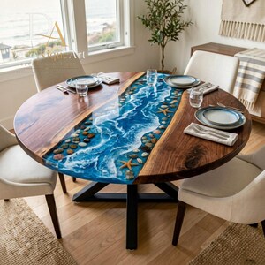 May include: A round dining table featuring a natural wood surface divided by a central resin inlay that mimics a blue ocean wave with white foam, embedded with small pebbles and starfish, supported by a black metal base with four chairs.