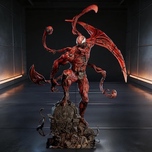 Puede incluir: Estatua detallada en rojo y negro del personaje Carnage de Marvel Comics. La figura está posada sobre una base de lápida con el nombre "Brock" visible. La estatua presenta detalles intrincados, incluyendo zarcillos y una expresión amenazante.