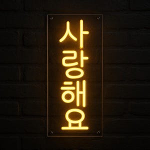 以下が含まれることがあります： 明るい黄色の光で韓国語の「사랑해요」という文字が浮かび上がる長方形のネオンサイン。透明なアクリルパネルに4つの銀色のコーナーボルトで固定されており、暗い背景に対して垂直に配置された発光するテキストが表示されています。