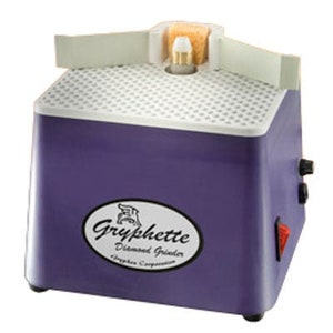 Puede incluir: Un molinillo de diamante Gryphette morado con una parte superior blanca y una pequeña esponja en el lateral. El molinillo tiene una superficie blanca en forma de rejilla y una etiqueta negra que dice "Gryphette Diamond Grinder Gryphon Corporation".