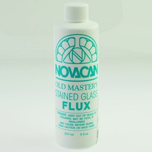May include: A white bottle with a turquoise label that reads "NOVACAN Old Master's Stained Glass Flux". The bottle contains 8 fluid ounces (237 ml) of flux.