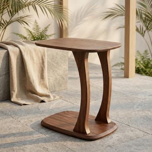 May include: A wooden side table with a rectangular top and curved legs. The table is made of dark brown wood and has a smooth finish. The base is also rectangular and made of the same wood. The table is approximately 61 cm long, 30 cm wide, and 61 cm tall.