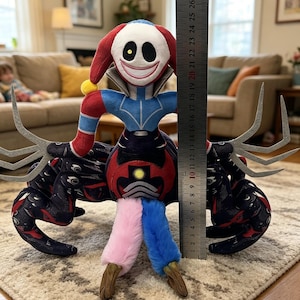 Puede incluir: Muñeco de peluche con cara de payaso, ropa roja y azul y apéndices negros. El muñeco mide aproximadamente 30 cm de alto. El muñeco tiene una cara sonriente con grandes ojos negros y un gorro de bufón rojo y blanco. Las piernas del muñeco son rosas y azules.