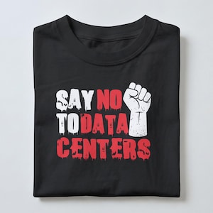 Peut inclure: Un t-shirt noir avec un motif graphique comprenant le texte blanc et rouge SAY NO TO DATA CENTERS et une icône de poing levé blanc. Le lettrage présente un effet de peinture dégoulinante et le t-shirt est plié soigneusement.