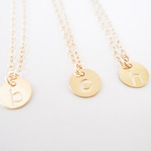 May include: Three gold necklaces with small round pendants featuring the letters 'b', 'c', and 'h'.