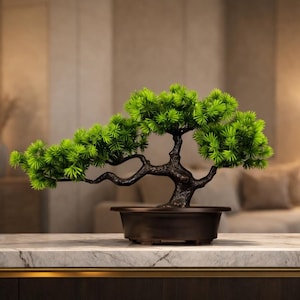 May include: A miniature bonsai tree with bright green foliage and a dark brown trunk. The tree is in a dark brown rectangular pot, set on a marble countertop. The background is a blurred interior scene with warm lighting.