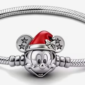 May include: A silver bracelet featuring a Mickey Mouse charm wearing a red Santa hat. The charm has Mickey's face and ears with star accents. The bracelet has a snake chain design.