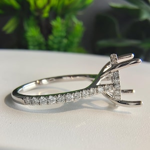 May include: A silver-toned metal ring setting featuring a high-profile prong head designed to hold a center stone. The band and the basket structure are encrusted with small, round, clear pavé-set stones along the shank and the prongs.