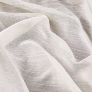 Könnte beinhalten: Ein transparenter, cremeweißer Stoff mit einer dezenten, horizontal gestreiften Textur. Das Material ist in weichen, fließenden Falten drapiert, was die leichte, halbtransparente Beschaffenheit und das feine, gewebte Gittermuster hervorhebt.