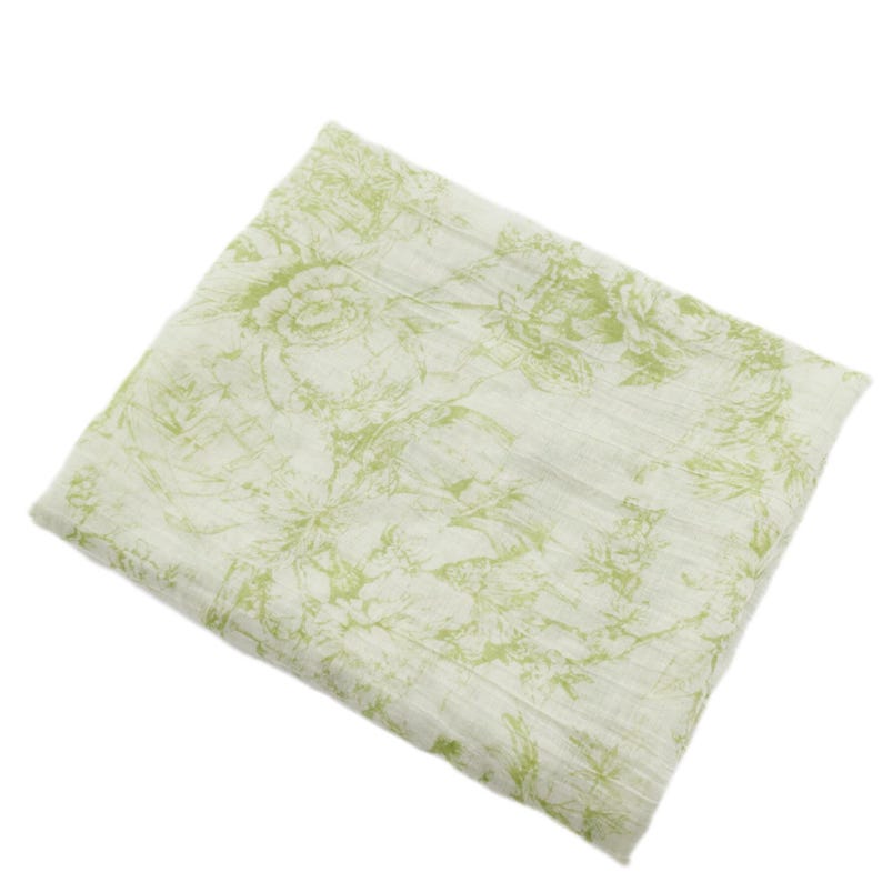 May include: A folded, off-white fabric with a repeating floral pattern in shades of green. The design features stylized roses and other botanical elements, creating a soft, textured appearance. The fabric appears lightweight and suitable for various uses.