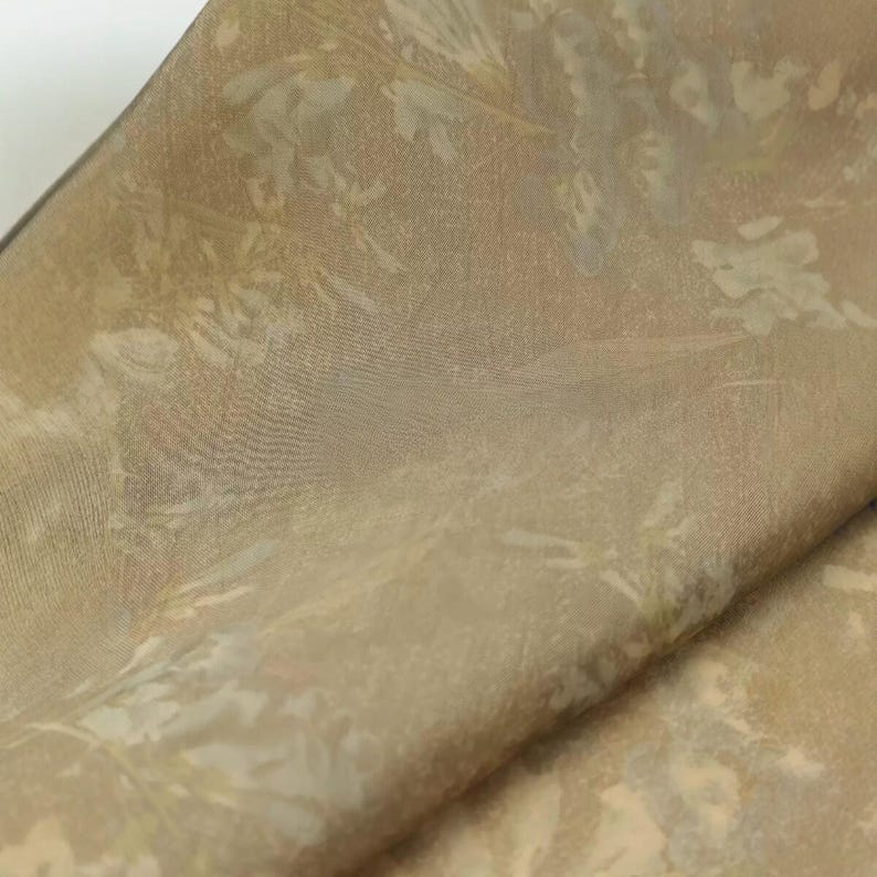 Puede incluir: Una pieza de tela de color marr&oacute;n claro con un sutil patr&oacute;n floral tonal. El material tiene una textura suave y ligeramente reflectante con un tejido delicado, mostrando un dise&ntilde;o monocrom&aacute;tico suave de hojas y flores en la superficie.