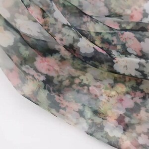 Pu&ograve; includere: Un tessuto trasparente con un motivo floreale nei toni del rosa, bianco, verde e nero. Il tessuto &egrave; drappeggiato, creando pieghe e ombre morbide. Il motivo floreale &egrave; denso e copre l'intera superficie.