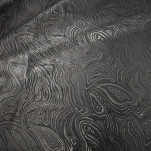 May include: A dark charcoal gray fabric featuring a continuous, flowing pattern of raised, metallic silver lines that create an intricate, swirling, marbled effect across the entire surface, with subtle textured details within the shapes.