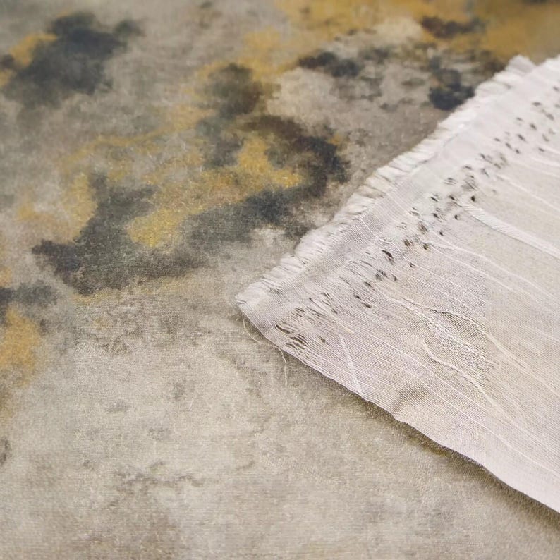 Peut inclure: Une pi&egrave;ce textile pr&eacute;sentant un motif abstrait et tachet&eacute; dans des tons de gris, charbon et jaune moutarde. Le tissu a un aspect textur&eacute; et vieilli avec un bord blanc semi-transparent effiloch&eacute; montrant des fils l&acirc;ches et un tissage d&eacute;licat.