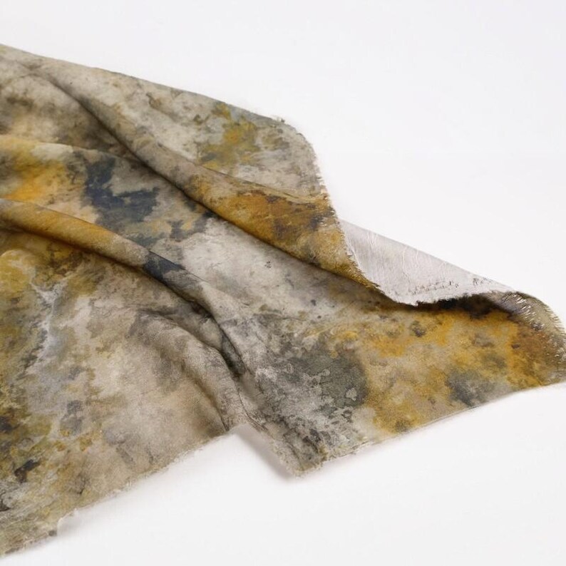 Peut inclure: Un morceau de tissu pr&eacute;sentant un motif abstrait et tachet&eacute; dans des tons de jaune moutarde, gris anthracite et blanc cass&eacute;. Le textile a un aspect textur&eacute; avec des taches de couleur in&eacute;gales et m&eacute;lang&eacute;es, ainsi que des bords effiloch&eacute;s.