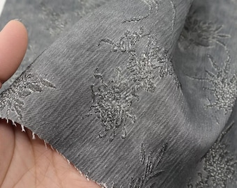 Tejido jacquard gris oscuro con drapeado en relieve y brillo sutil, estampado de hojas de bambú y orquídeas.