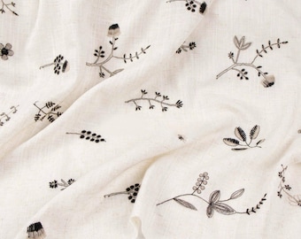 Tela de lino beige, bordado botánico elaborado, caída suave, material para coser.