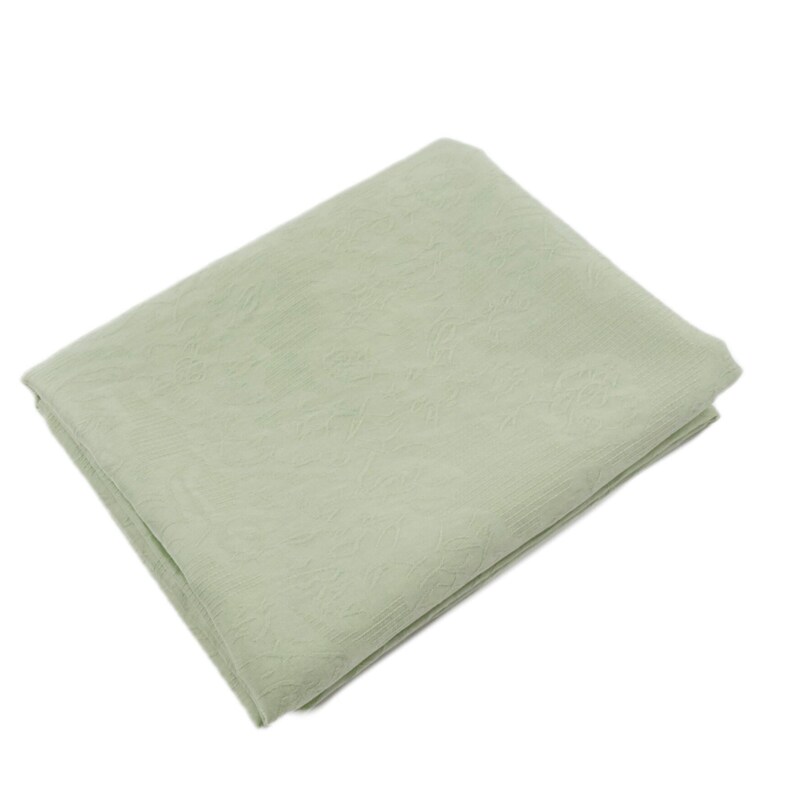 May include: A folded, light green blanket with a subtle floral pattern. The blanket is rectangular and appears to be made of a soft, textured fabric. The color is a muted, pastel green.