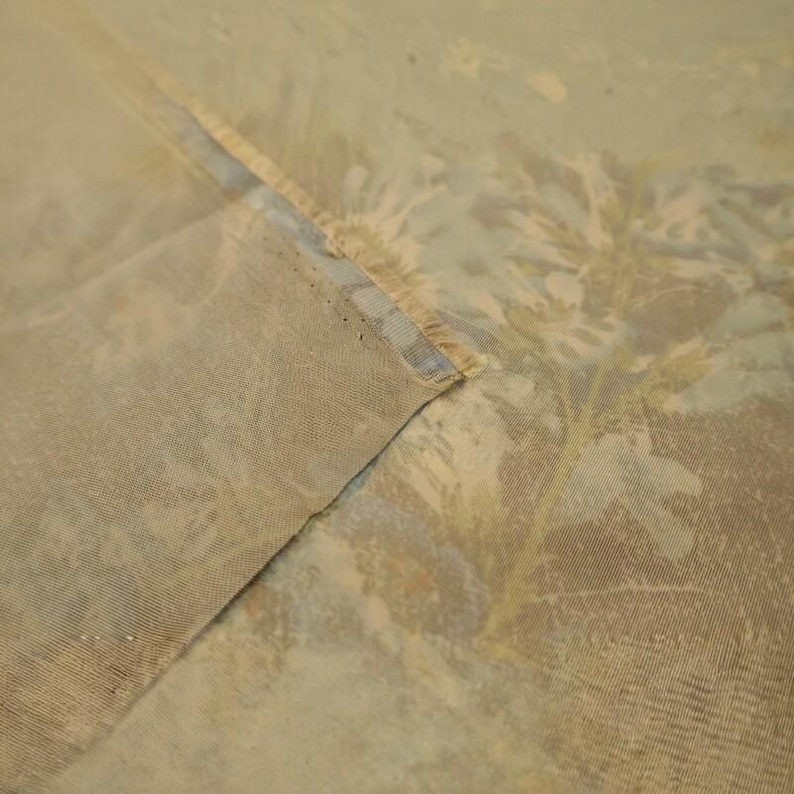 Puede incluir: Una pieza de tela semitransparente de color marr&oacute;n claro con un sutil patr&oacute;n floral desvanecido en tonos apagados. El material tiene un tejido visible y un borde doblado, mostrando una calidad semitransparente con una paleta de colores tierra.