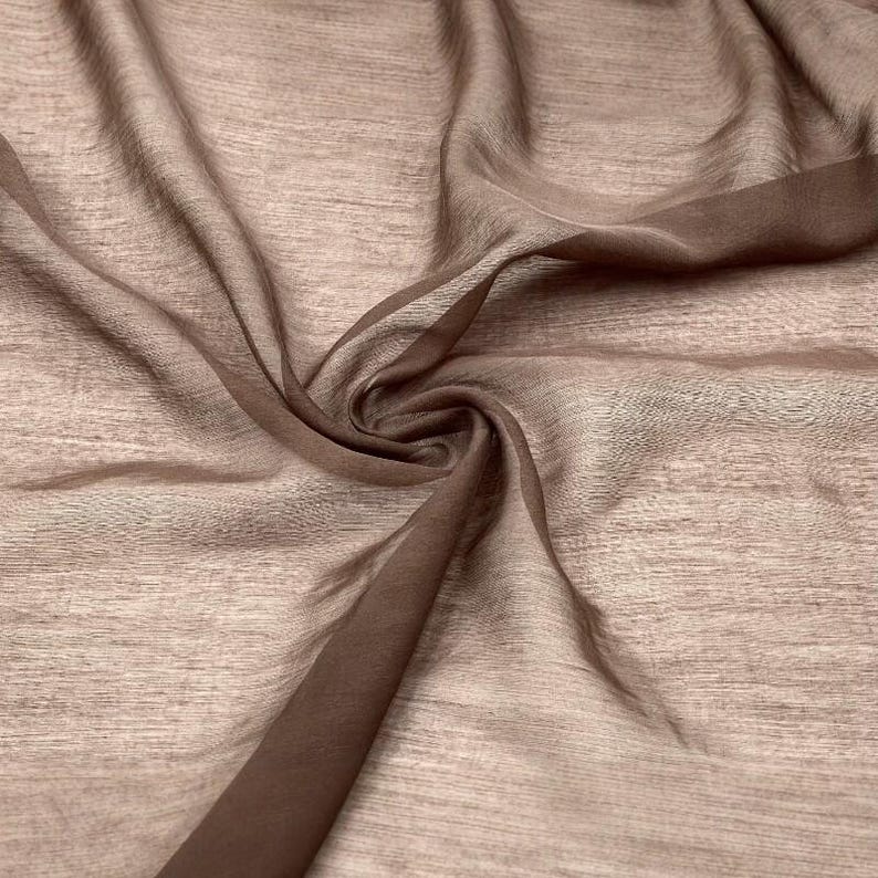 K&ouml;nnte beinhalten: Ein transparenter, leichter Stoff in einem ged&auml;mpften Taupe- oder Hellbraunton. Das Material weist eine feine, horizontale Webstruktur auf und ist in weichen, flie&szlig;enden Falten drapiert, die seine Transparenz und Zartheit unterstreichen.
