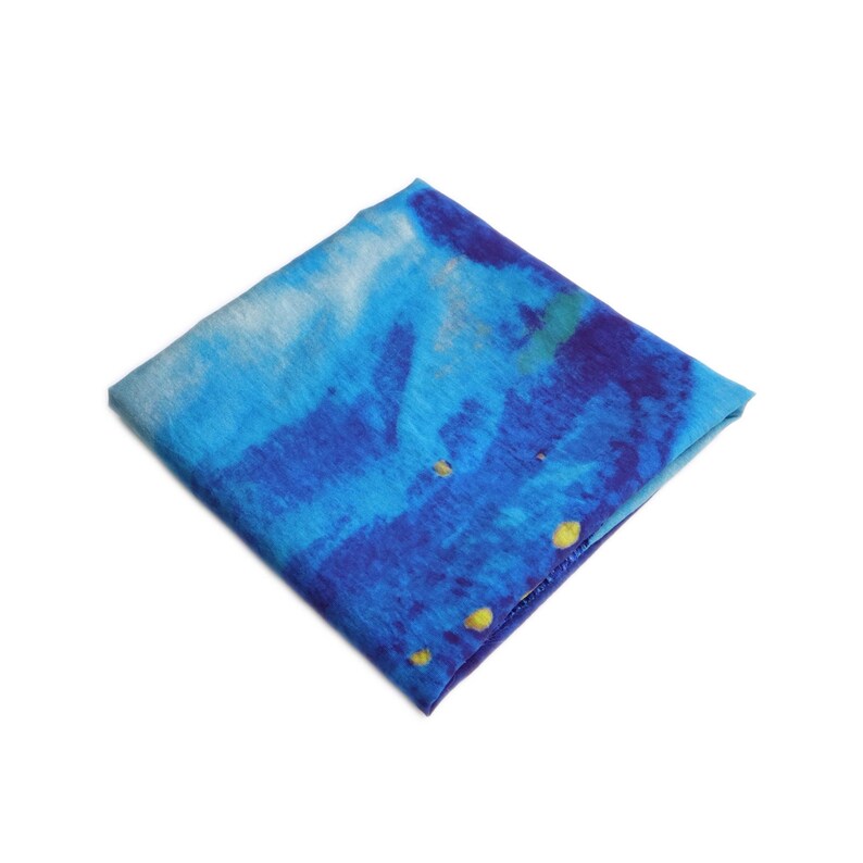 May include: Square blue and white patterned fabric with yellow accents. The fabric has a watercolor-like design with shades of blue and white. The fabric is folded into a square shape.