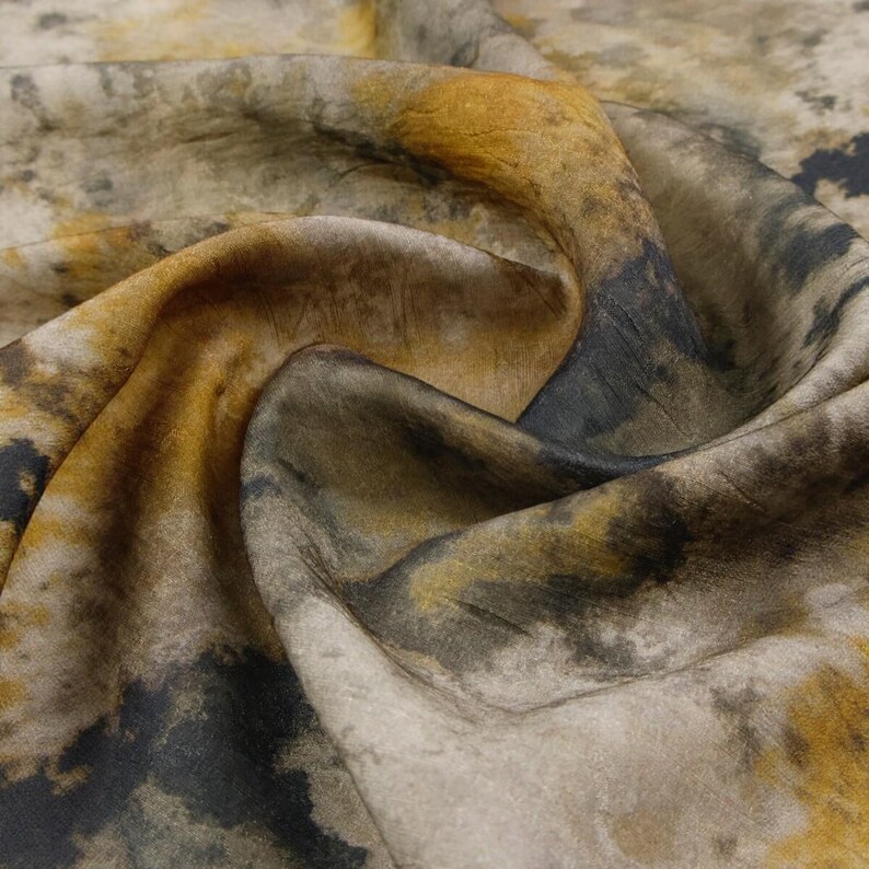 Peut inclure: Un morceau de tissu pr&eacute;sentant un motif abstrait avec des nuances m&eacute;lang&eacute;es de jaune moutarde, de gris anthracite et de blanc cass&eacute;. Le mat&eacute;riau a une texture douce et drap&eacute;e avec des plis visibles qui cr&eacute;ent de la profondeur et soulignent.