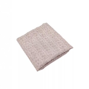 May include: A folded, light beige waffle-weave blanket. The blanket is square and appears to be made of a soft, textured material. The weave pattern creates a grid-like design across the surface. The blanket is on a white background.