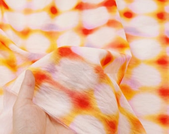 Tela de mezcla de Tencel y lino con estampado tie-dye, anillos beige, naranja y morado, caída suave, ideal para costura de estilo resort.