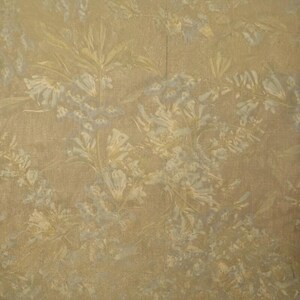 May include: A close-up of a wallpaper with a floral pattern. The background is a warm, golden-brown color, with a subtle texture. The floral design features delicate, light-colored flowers and leaves, creating a soft, elegant look.
