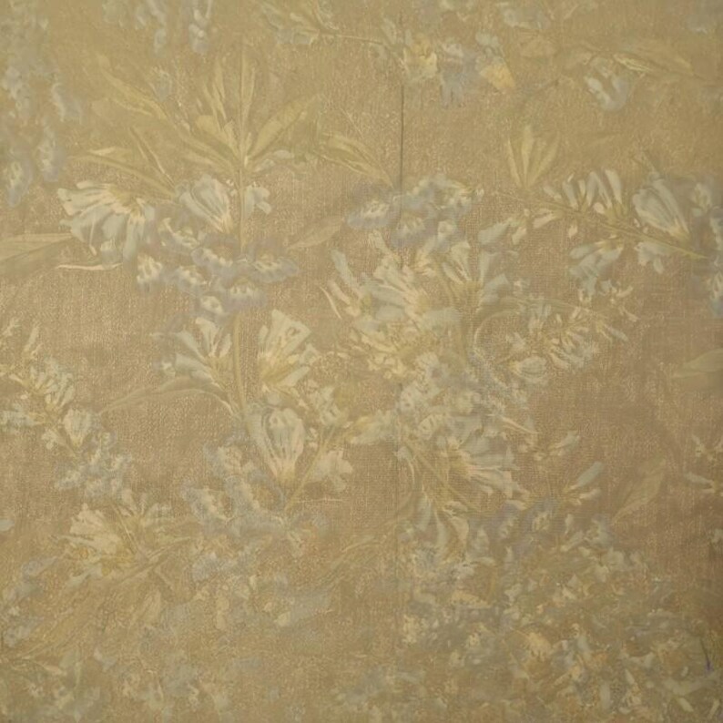 May include: A close-up of a wallpaper with a floral pattern. The background is a warm, golden-brown color, with a subtle texture. The floral design features delicate, light-colored flowers and leaves, creating a soft, elegant look.