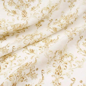 May include: Close-up of a cream-colored fabric with a repeating gold damask pattern. The fabric is folded, creating shadows and highlighting the texture of the material. The design features ornate floral and scroll motifs.