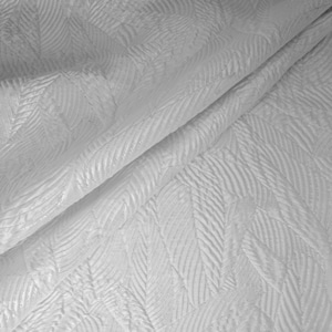 May include: A solid white fabric featuring a raised, textured pattern of repeating fern-like leaves. The material is folded, creating diagonal shadows that highlight the embossed, three-dimensional surface of the botanical leaf design.