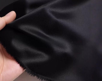 Tejido de satén de triacetato negro, de gran gramaje y caída sedosa, con un sutil brillo. Textil de diseño.