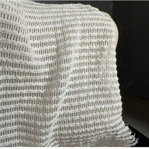 Peut inclure: Gros plan sur un tissu blanc à tissage ouvert. Le matériau présente un motif texturé en forme de grille avec des ouvertures rectangulaires. Le tissu semble être drapé, avec des plis visibles et une surface légèrement inégale. L'impression générale est celle d'un textile léger et respirant.