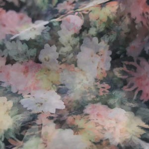 Pu&ograve; includere: Primo piano di un tessuto con motivo floreale. Il design presenta fiori morbidi, simili ad acquerelli, in tonalit&agrave; di bianco, rosa e giallo su uno sfondo scuro. L'effetto complessivo &egrave; delicato e romantico.