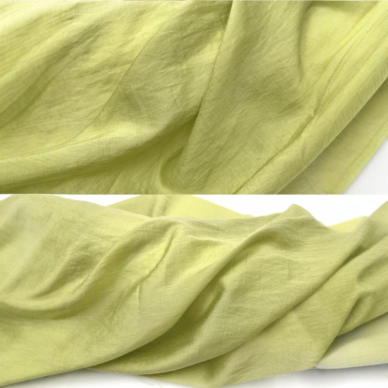 May include: A light lime green fabric with a fine, semi-sheer texture and a subtle horizontal weave pattern. The material is draped in soft, flowing folds, showcasing its lightweight quality and consistent, vibrant yellow-green color throughout.