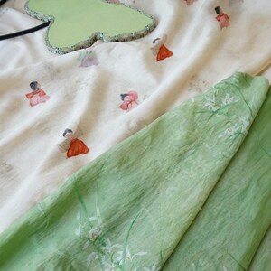 Peut inclure: Vue a&eacute;rienne d'un miroir vert clair en forme de feuille avec une bordure &agrave; motifs, et d'un tissu cr&egrave;me avec de petites figures color&eacute;es imprim&eacute;es dessus. Un tissu vert clair avec des motifs floraux blancs est &eacute;galement visible.
