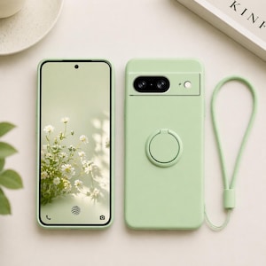 May include: Two light green phone cases, one with a phone displaying a floral wallpaper. The other case has a camera cutout, a ring holder, and a matching green wrist strap. The phone screen shows a floral design.