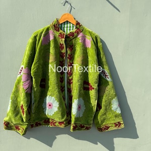 Könnte beinhalten: Eine limettengrüne Samtjacke mit floralen Stickereien in Rosa, Weiß und Burgunderrot. Die Jacke hat einen Reißverschluss vorne und ein reversibles Design mit einem grün-weiß karierten Muster auf der Innenseite. Der Text "NoorTextile" ist sichtbar.