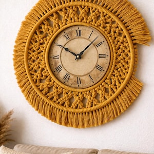 May include: Mustard yellow macrame wall clock with a vintage-style clock face featuring Roman numerals. The clock is surrounded by a circular macrame design with fringe detailing, adding a bohemian touch to home decor.